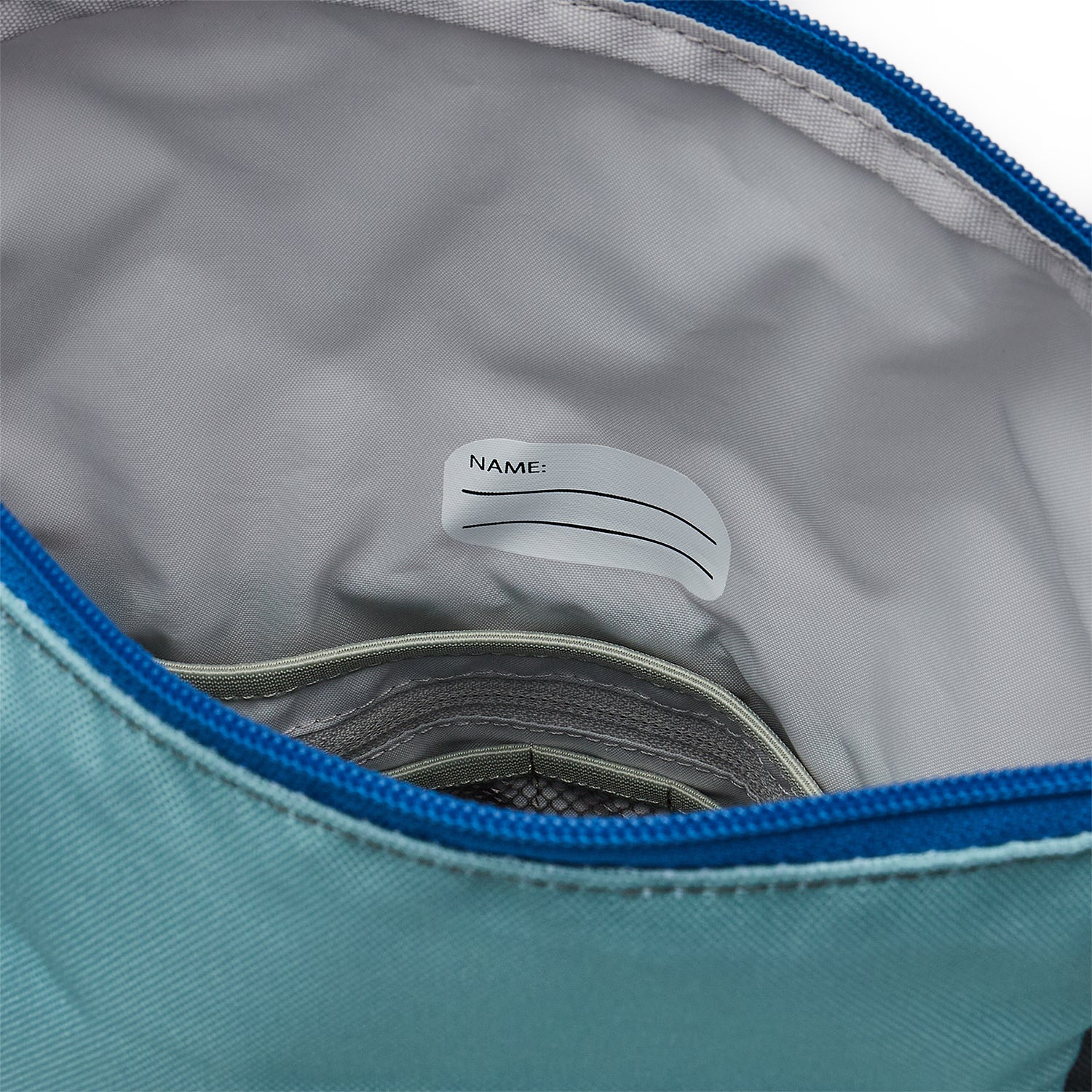 Ela Mo™ Kinderrucksack (6-10 Jahre) | Blue Mint. Der graue Innenbereich des Rucksacks mit einem Namensschild.