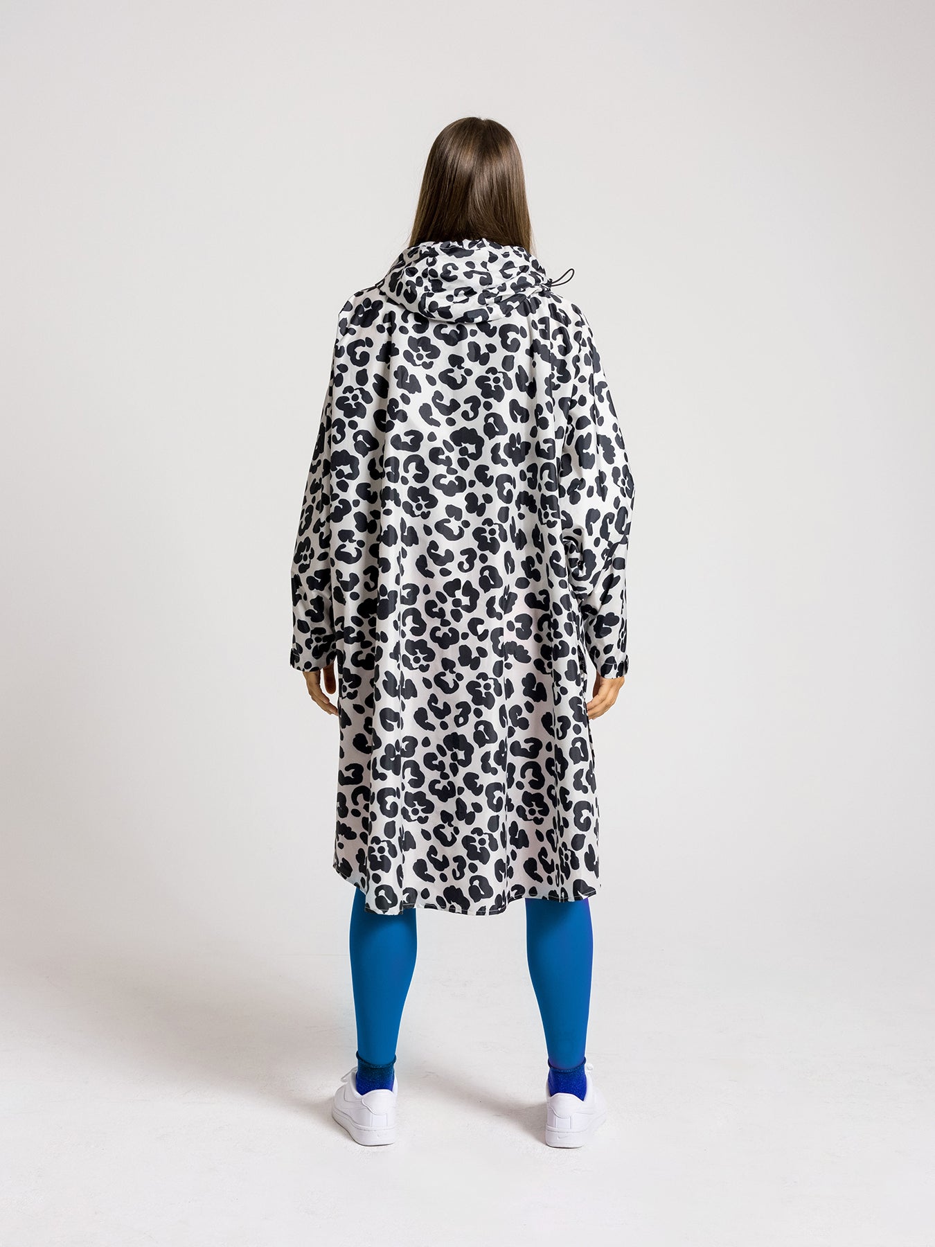 Ela Mo™ Regenponcho | Leo. Frau mit Regenponcho von hinten auf weißem Hintergrund.