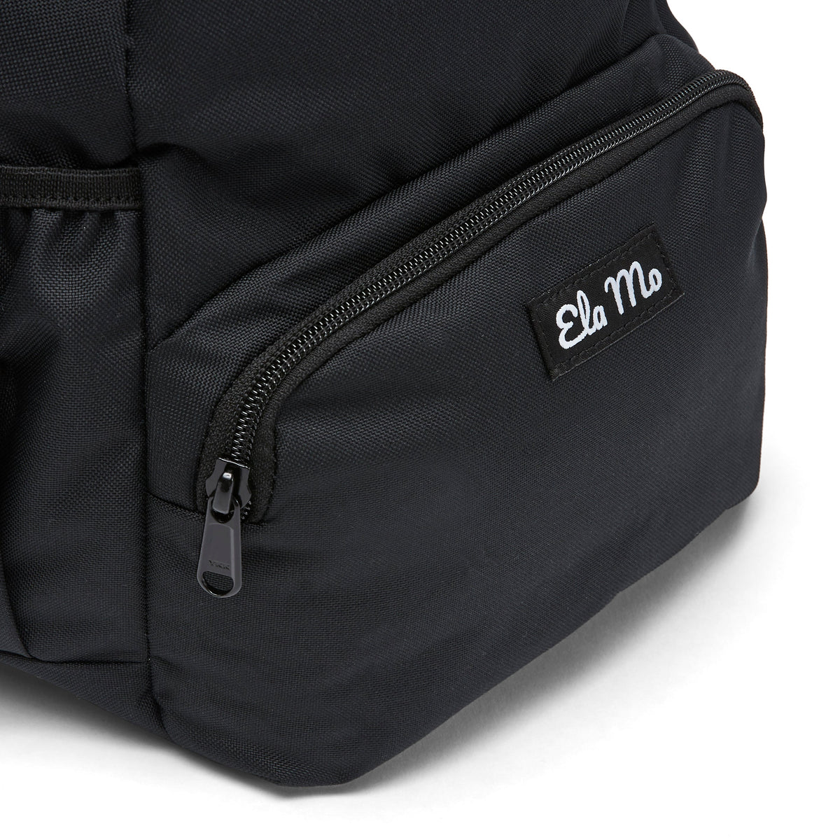 Ela Mo™ Mini Rucksack | Schwarz. Außenfach mit Herstellerlogo auf der Vorderseite des Rucksacks.