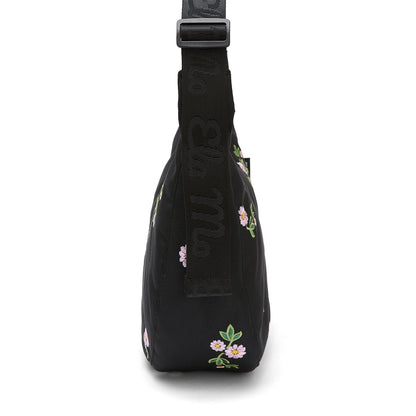 Ela Mo™ Moon Bag | Embroidery Edition Upsy Daisy. Umhängetasche von der Seite, mit schwarzem, verstellbarem Schulterriemen.